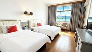 A hotel room with two beds, a desk, a chair, a TV, and a window with a view. - Huanqiu Hotel (Ninghai)