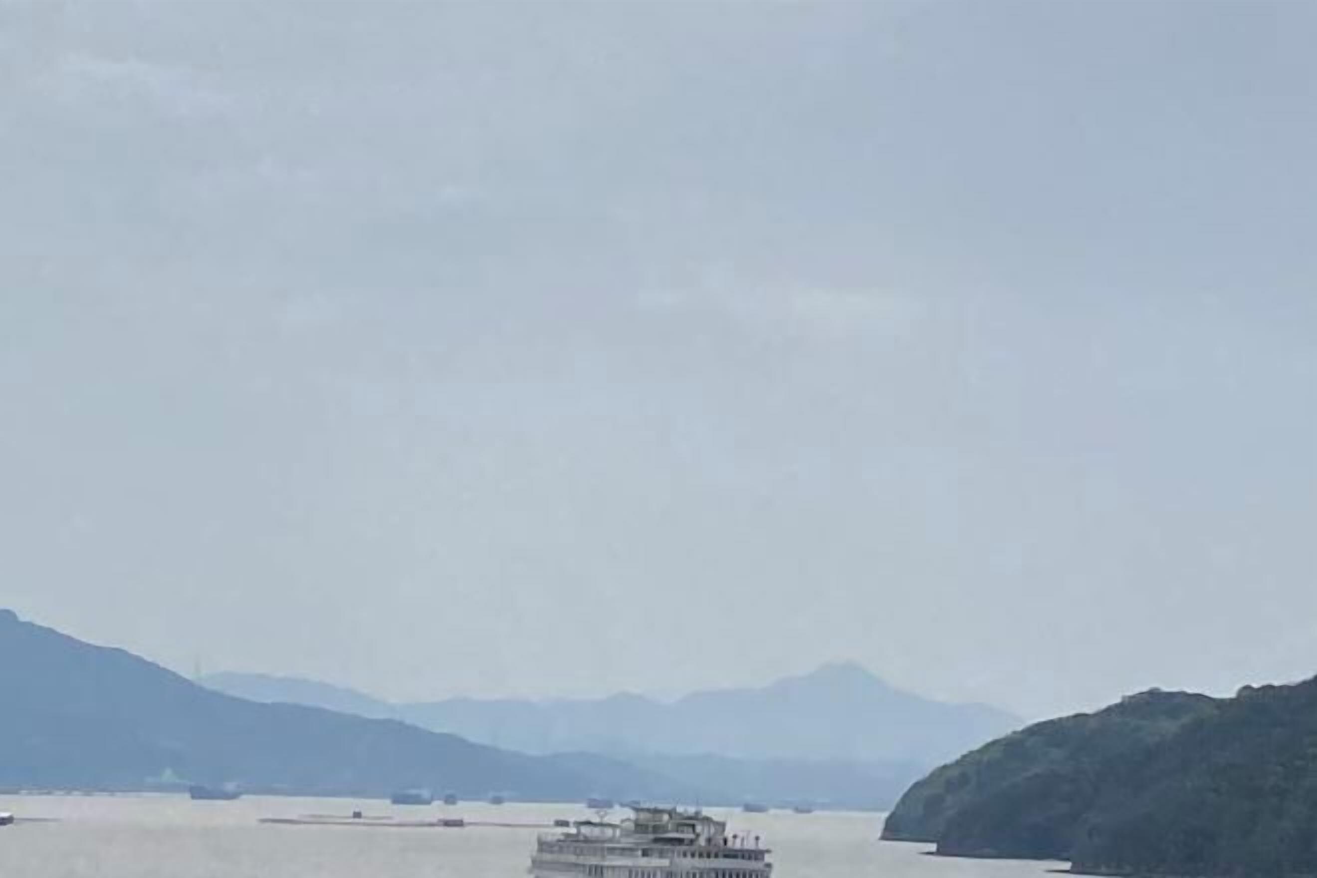 A large body of water with a boat in the foreground and mountains in the background.