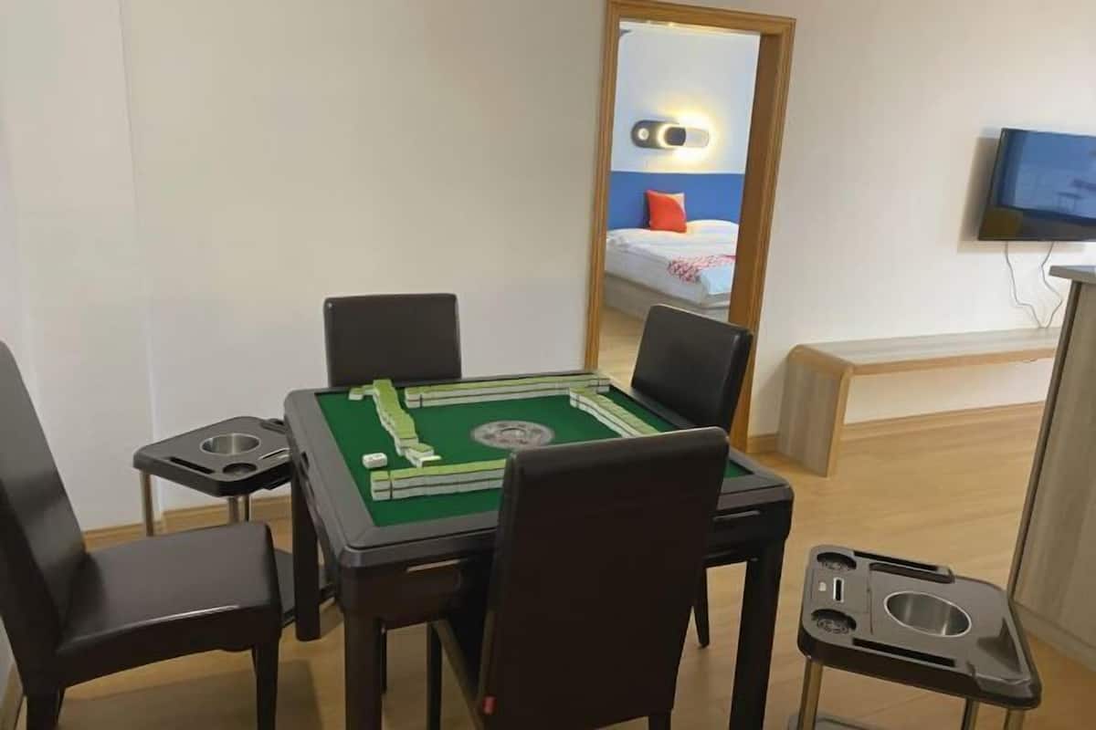 Huoneessa on biljardipöytä, tuoleja, sänky, jossa on televisio, ja peili.