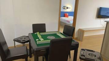 A room with a pool table, chairs, a bed with a TV, and a mirror.