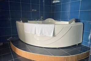 Un baño moderno con una bañera independiente, una toalla y paredes de azulejos azules.
