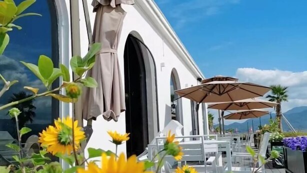 An outdoor seating area with white tables and chairs, sunflowers, and umbrellas. - Huanqiu Hotel (Ninghai)