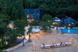 A resort with a large swimming pool, a covered outdoor seating area, and a building with a distinctive architectural style. - Huanqiu Hotel (Ninghai)