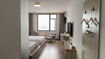 A hotel room with a bed, a desk, a chair, a TV, and a window.