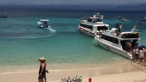 A beach with boats, a person in a hat, and scuba tanks on the sand. - Huanqiu Hotel (Ninghai)