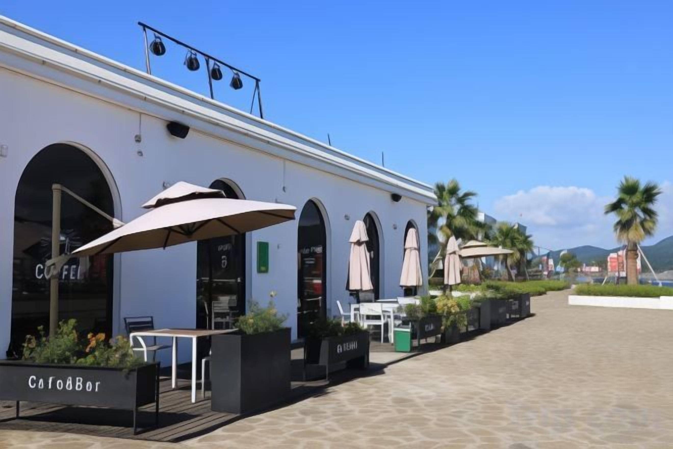 A cafe with outdoor seating, a sign reading 'CafodBar,' and a clear blue sky.
