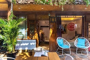 A wooden exterior with a traditional entrance, a potted plant, and two white wicker chairs with blue cushions. - Lijiang Clouds flying high Inn (Lijiang)