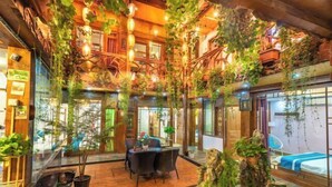 A cozy indoor space with a wooden floor, a dining area with chairs, and a bed. - Lijiang Clouds flying high Inn (Lijiang)