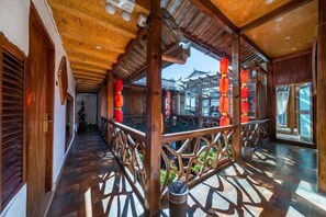 Un couloir orné de poutres en bois, de lanternes rouges et offrant une vue sur une architecture traditionnelle.