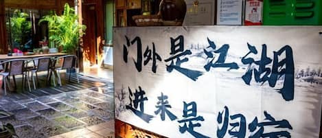 A traditional Chinese restaurant with a signboard, outdoor seating, and a tiled floor.