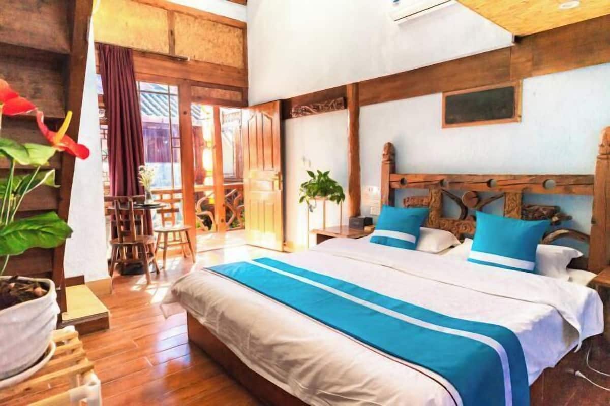 A bedroom with a large bed, wooden walls, a small table, and chairs.