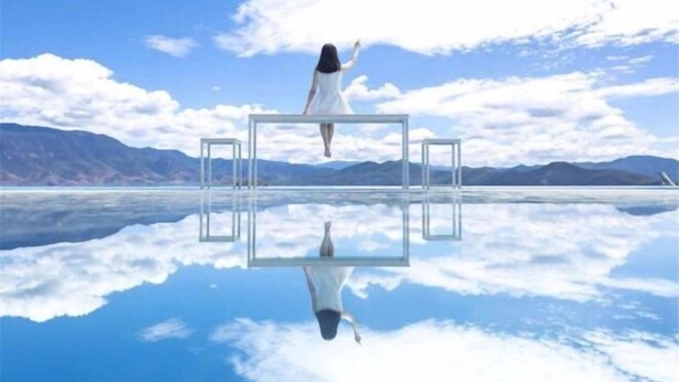 A person standing on a transparent platform with a clear view of the sky and mountains in the background. - Lijiang Clouds flying high Inn (Lijiang)