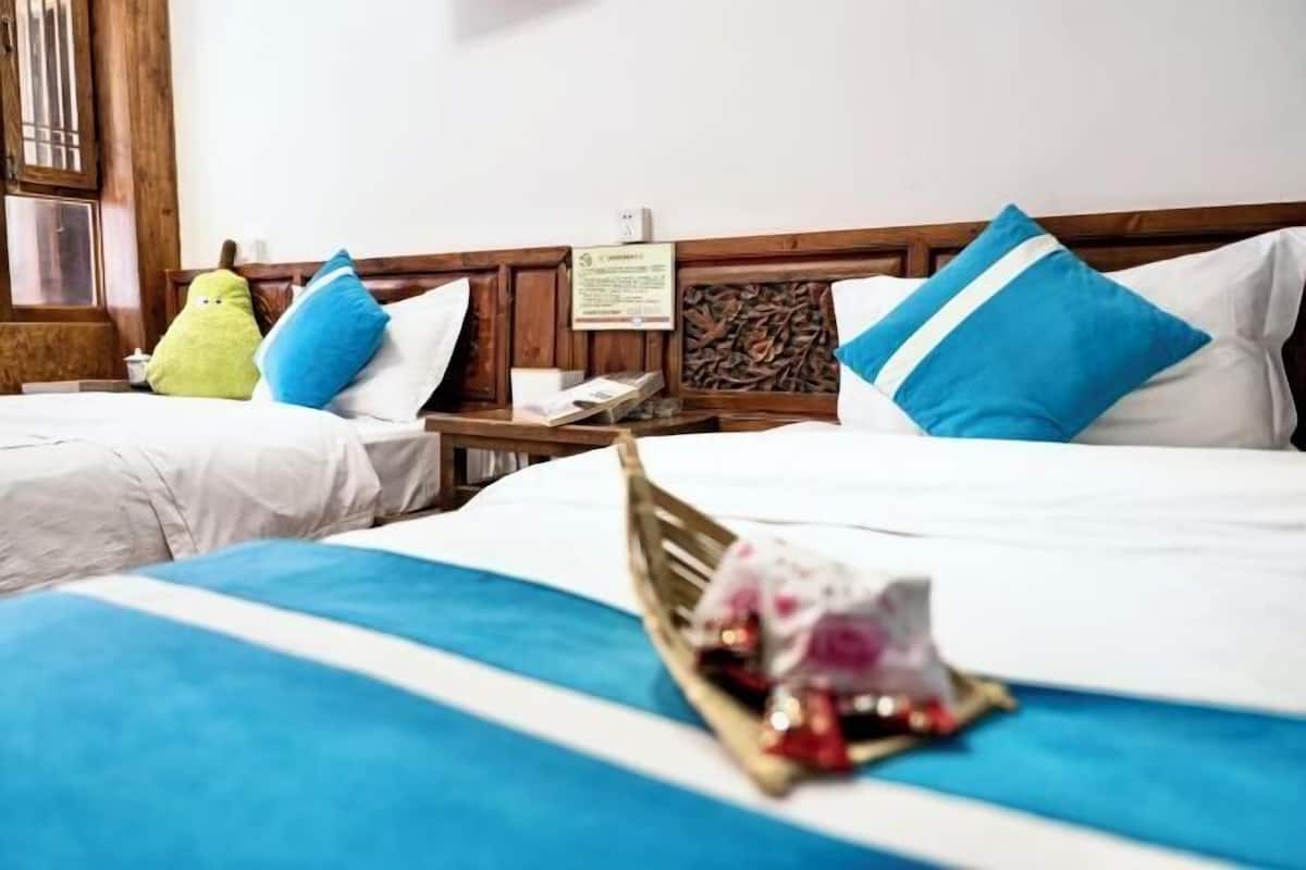A hotel room with two beds, a wooden headboard, and a bedside table with a lamp.