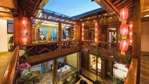 A multi-level wooden interior with a balcony, wooden railings, and hanging red lanterns. - Lijiang Clouds flying high Inn (Lijiang)