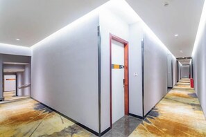 A hotel corridor with a carpeted floor, a red door, and a sign indicating the room number. - Oushi Express Hotel (Guangzhou Lansha Lanhe) (Guangzhou)