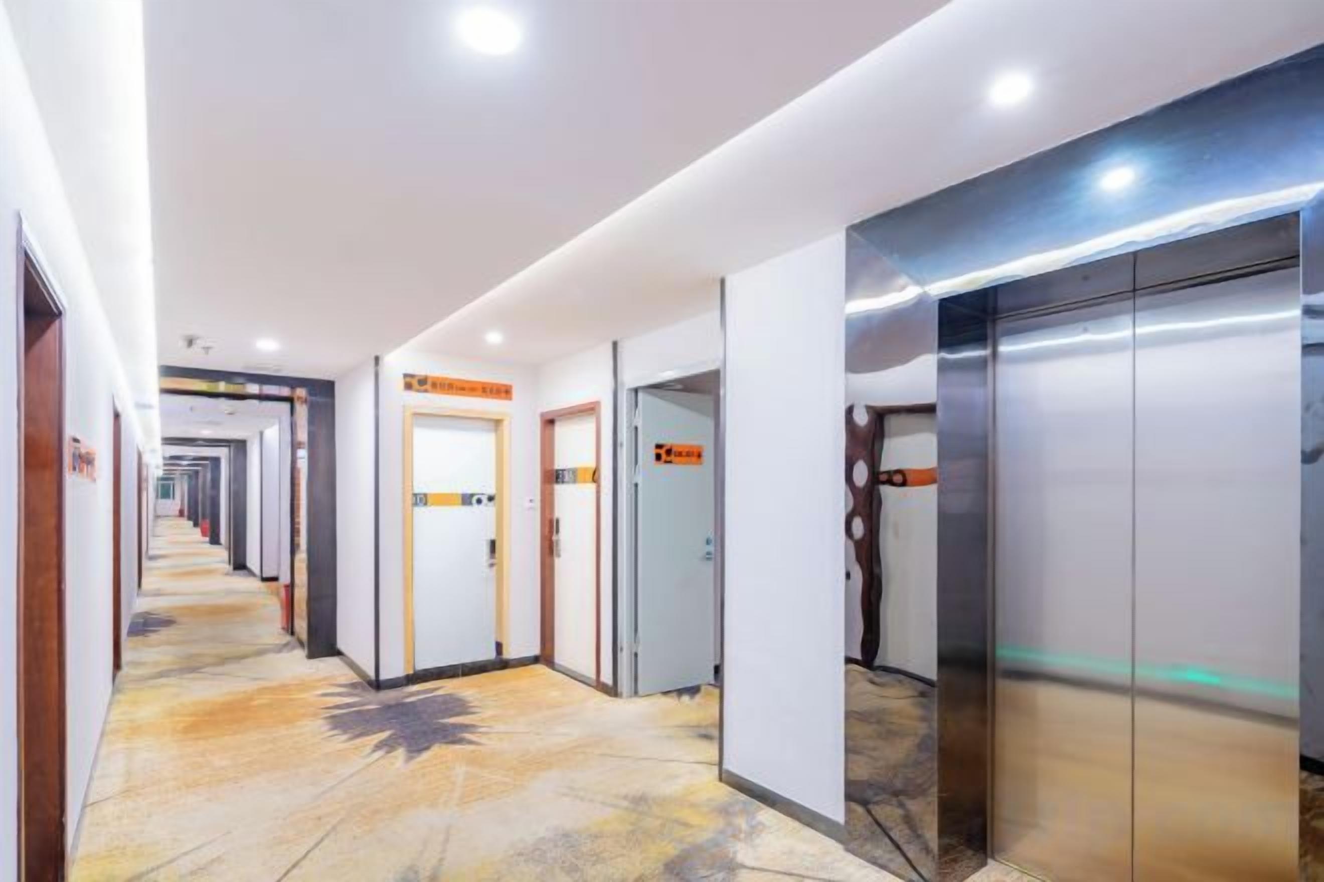 Un pasillo de hotel con varias puertas, ascensores y un suelo estampado.