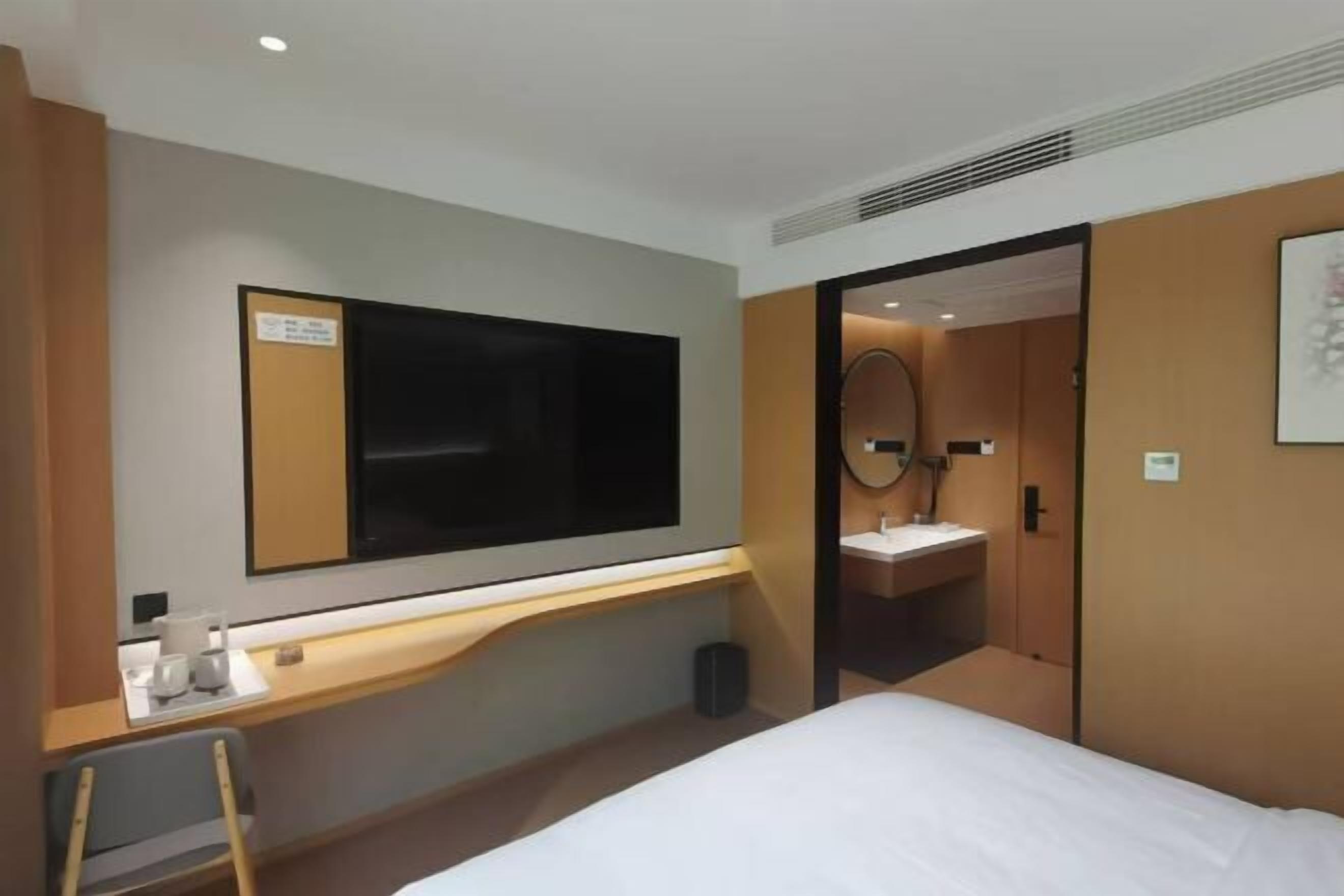 Una habitación de hotel con cama, escritorio, silla, televisión y baño.