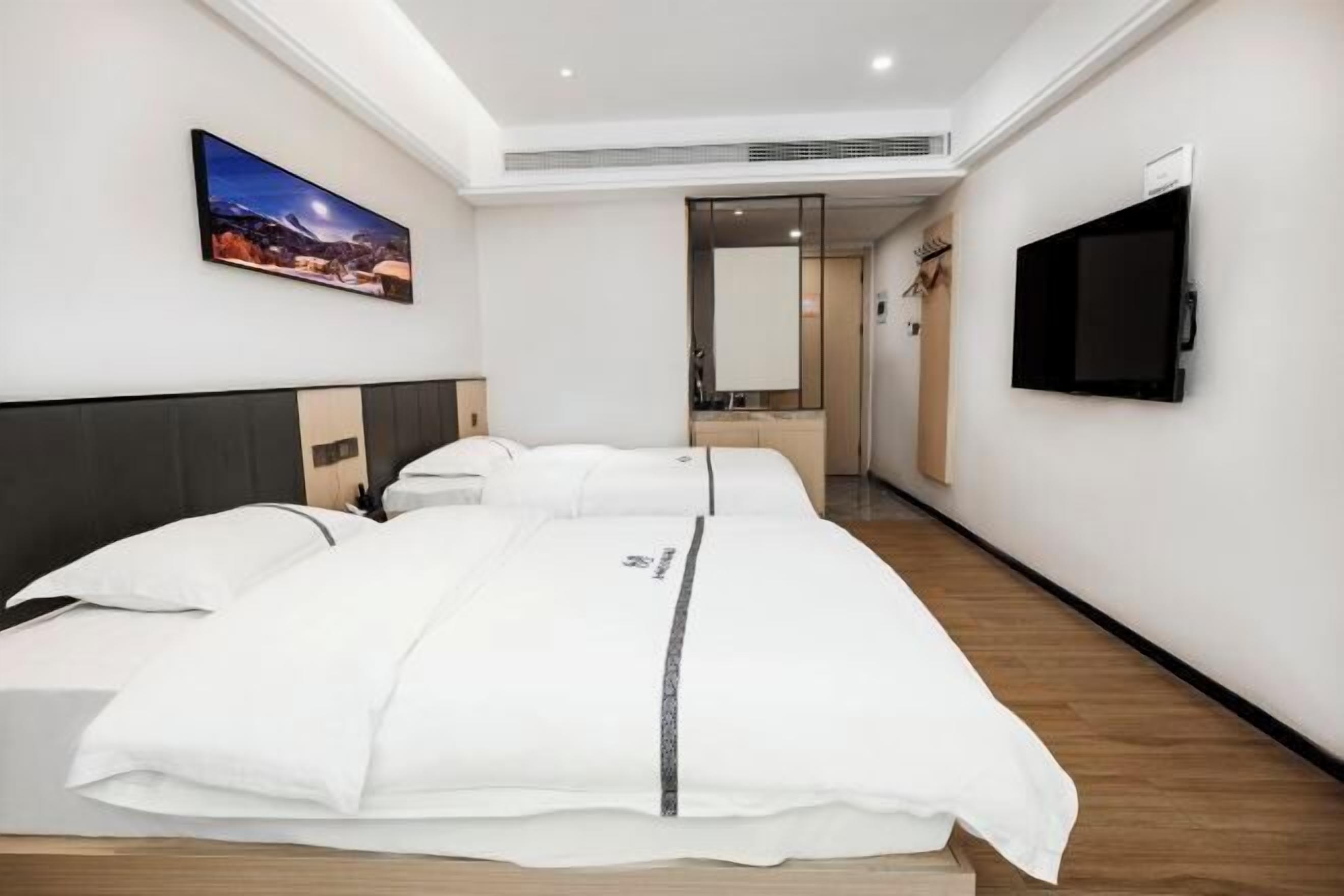 Ein Hotelzimmer mit einem großen Bett, einem an der Wand befestigten Fernseher und einem Bild an der Wand.