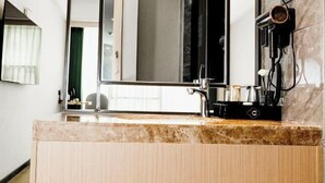 Ein modernes Badezimmer mit Marmorplatte, einem großen Spiegel und einem an der Wand befestigten Föhn.