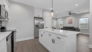 A modern kitchen with white cabinetry, a central island, and built-in appliances.
