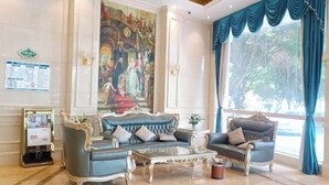 A spacious lobby with a large mural, two sofas, a coffee table, and a reception desk.