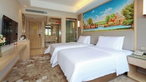 A hotel room with two beds, a painting on the wall, a TV, and a desk with a phone.