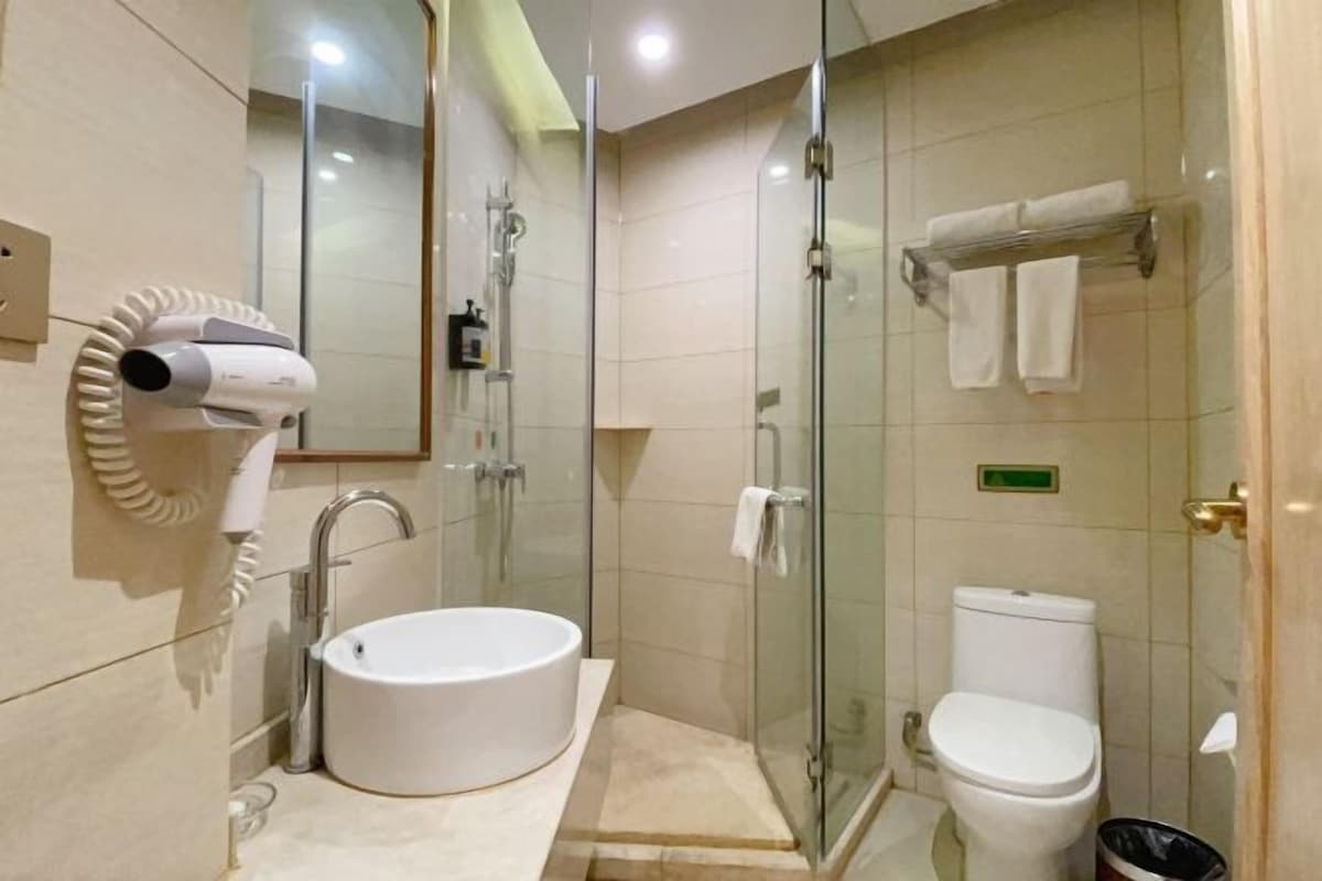 A modern bathroom with a glass-enclosed shower, a standalone sink, and a toilet.