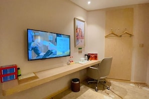 A hotel room with a desk, a television mounted on the wall, a chair, a coat rack, and a trash bin. - Vienna Classic Hotel (Chongqing Bishan Aokang) (Chongqing)