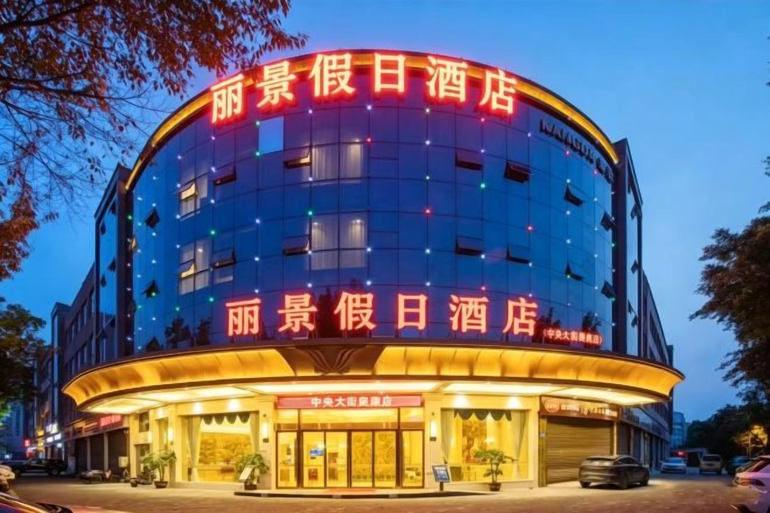 A hotel with a curved facade, multiple floors, and illuminated signage.