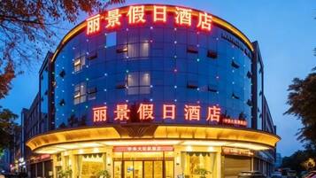 A hotel with a curved facade, multiple floors, and illuminated signage.