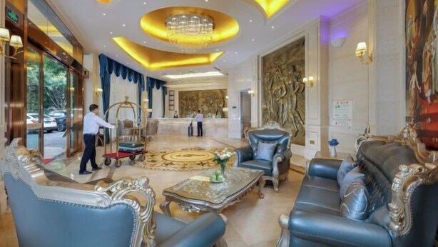 A luxurious lobby with ornate furniture, a grand chandelier, and a reception desk.