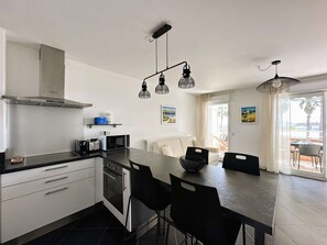 Una cocina moderna con comedor, que incluye horno empotrado, microondas y campana extractora de acero inoxidable.