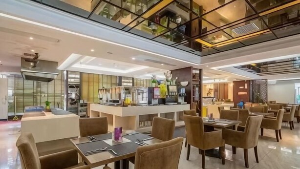 A modern dining area with tables and chairs, a kitchen in the background, and a high ceiling with exposed beams. - Hualong Golden Key Hotel (Songxi)