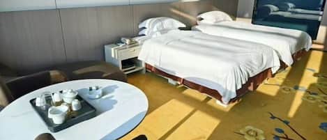 A hotel room with two beds, a small table with tea service, and a large window.