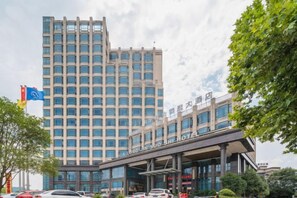 A multi-story hotel with a modern design, featuring a prominent entrance and a large glass facade. - Hualong Golden Key Hotel (Songxi)