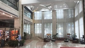 A spacious lobby with a high ceiling, large windows, and a staircase leading to an upper level. - Hualong Golden Key Hotel (Songxi)