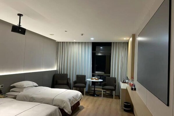 A hotel room with two beds, a small table, two chairs, a TV, and a projector. - Hualong Golden Key Hotel (Songxi)