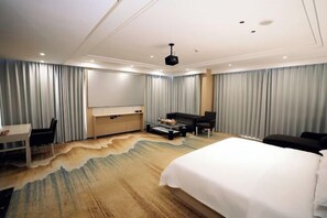 A hotel room with a bed, a desk, a sofa, a coffee table, and curtains. - Hualong Golden Key Hotel (Songxi)