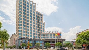 A multi-story hotel with a modern facade, a prominent entrance, and a flag. - Hualong Golden Key Hotel (Songxi)