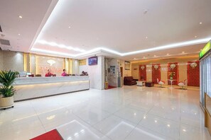 A hotel reception area with a marble counter, seating area, and a television screen. - Red Lantern Traders Hotel (Nanning)