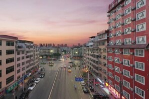 Un edifici de diversos pisos amb una carretera central, envoltat d'altres edificis.