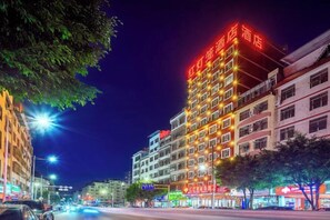 A multi-story hotel with illuminated signage, a street view with vehicles, and a clear night sky. - Red Lantern Traders Hotel (Nanning)