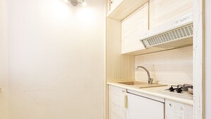 Una pequeña cocina con un lavamanos, estufa y armarios.