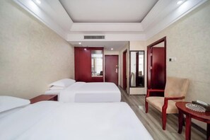 Une chambre d’hôtel avec deux lits, une chaise en bois, une petite table et un miroir.