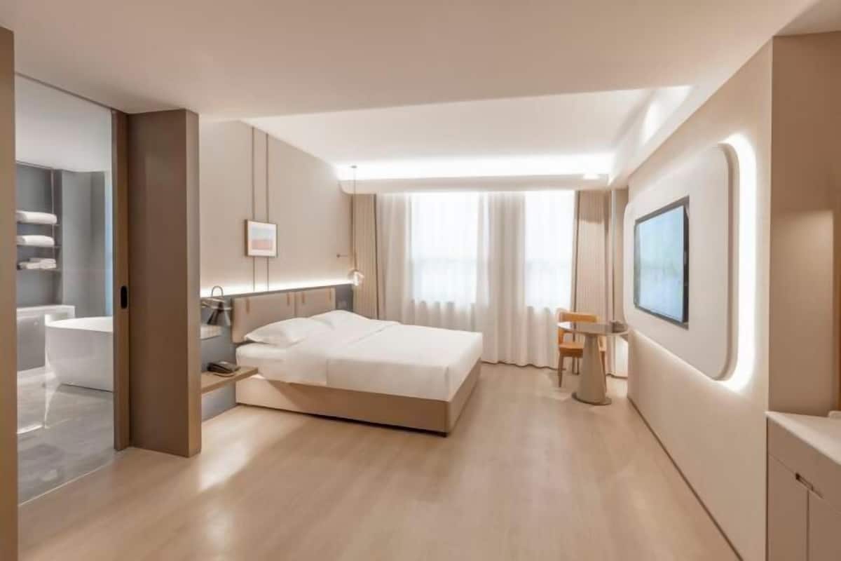 A modern hotel room with a bed, bedside table, and a view of the bathroom.