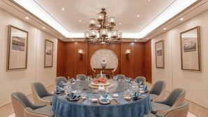 Une salle de conférence équipée d’une table ronde, de chaises et d’un lustre.