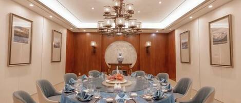 A conference room with a round table, chairs, and a chandelier.