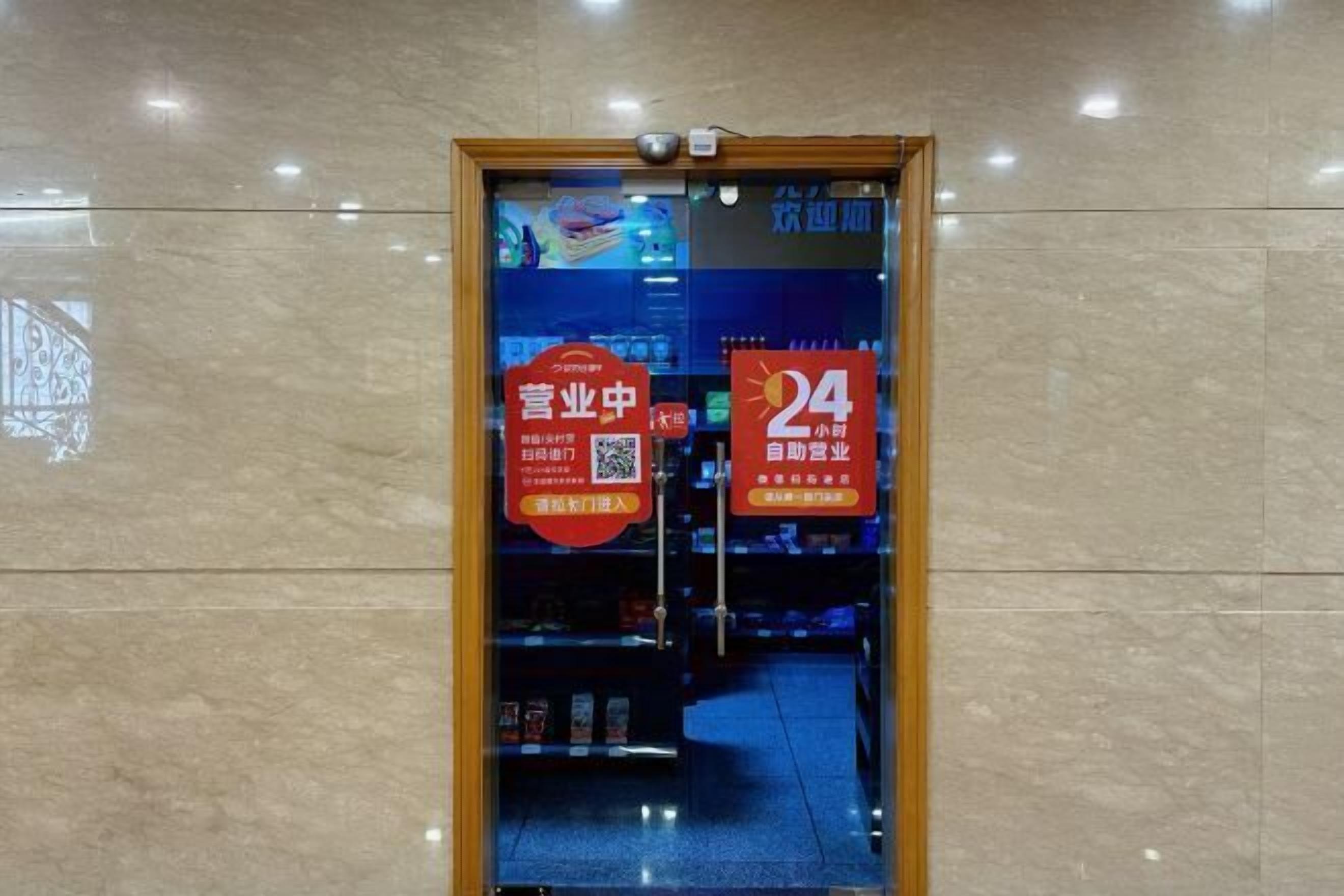 A hotel entrance with a glass door, two red promotional signs, and a blue interior visible through the glass.