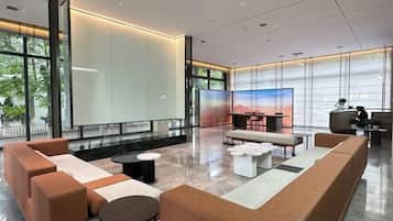 A modern lobby with seating areas, a reception desk, and large windows.