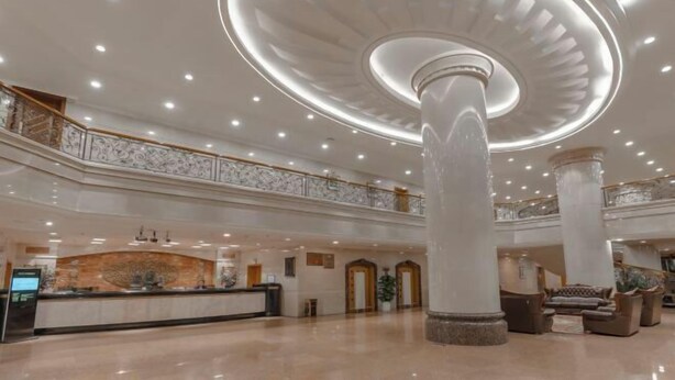 Un hall d’entrée spacieux avec une colonne centrale, un comptoir d’accueil et un escalier.